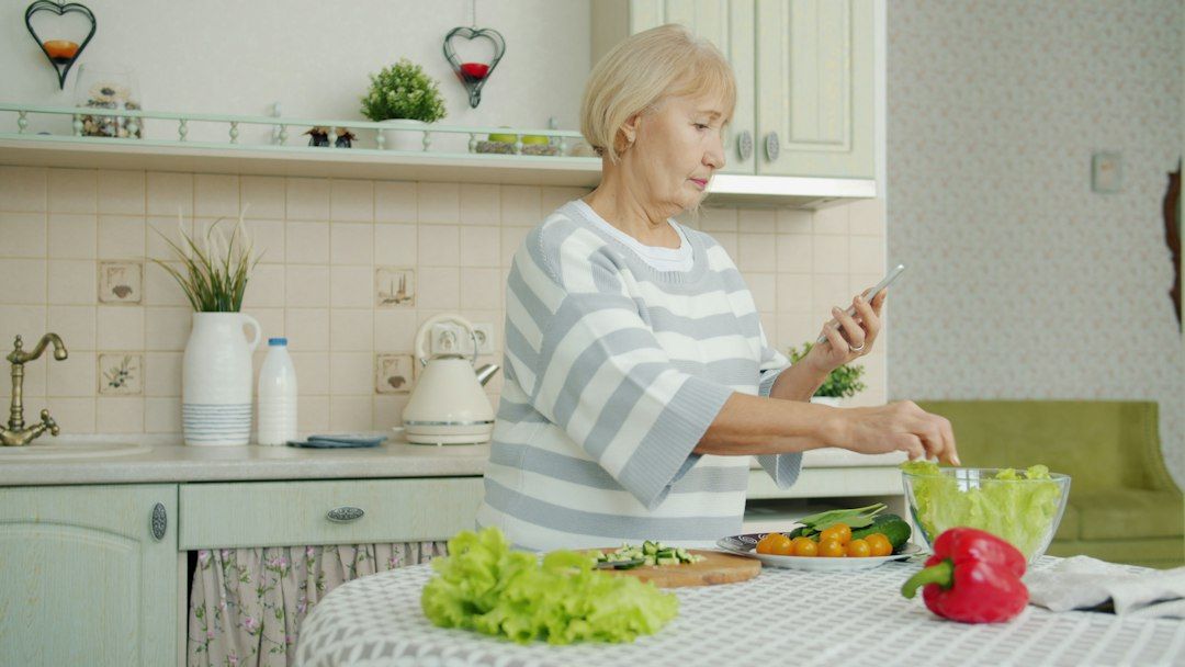 Mujer preparando una ensalada en casa, nutrición para personas mayores